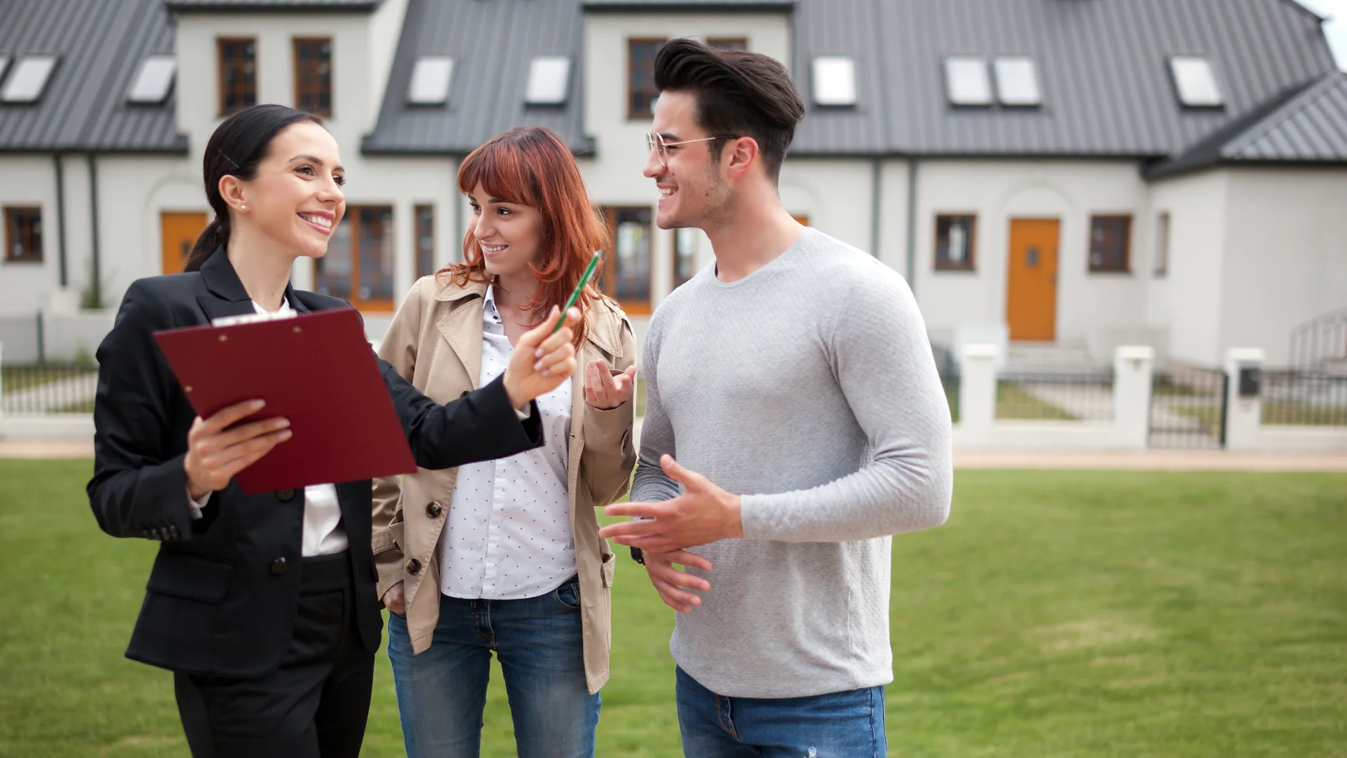 Young couple with real estate agent visiting house for sale in residential area