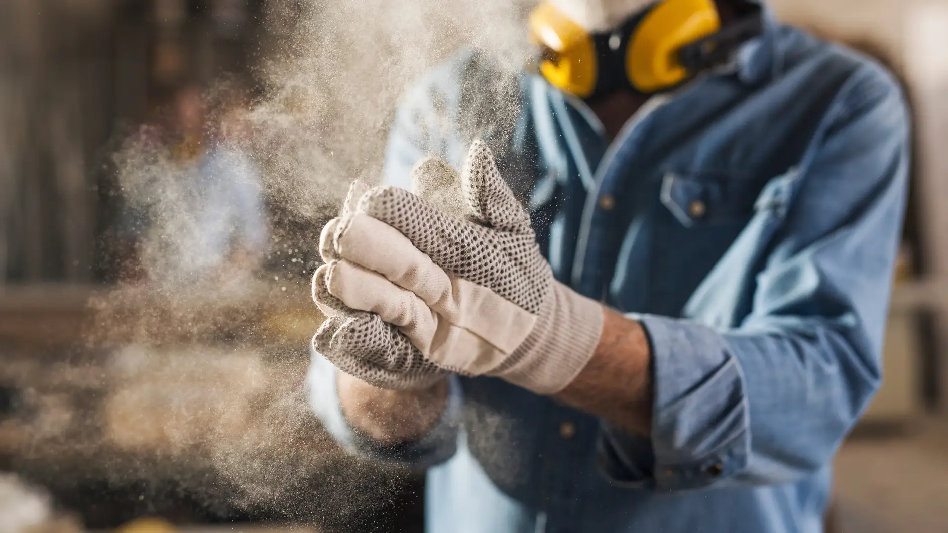 Close up of an unrecognizable male hands with work gloves on, clapping to remove sawdust